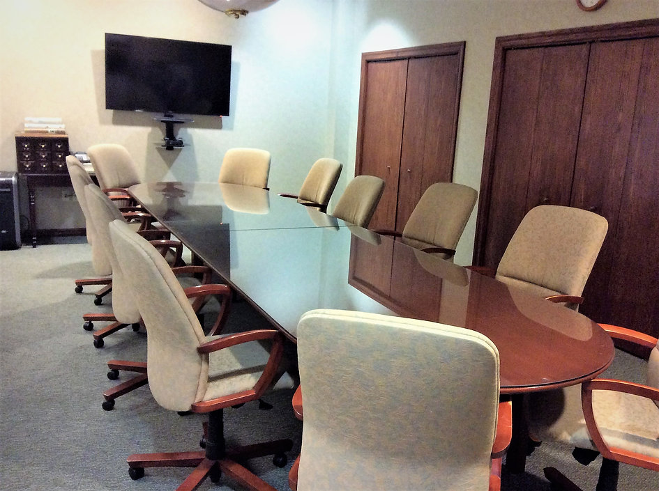 The conference room has a TV monitor plus a long table, surrounded by about 14 upholstered chairs.